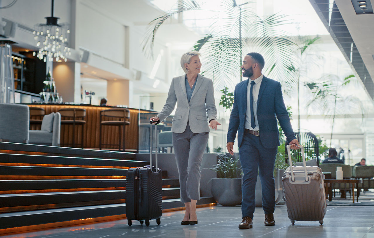 happy business woman and man chatting and walking with luggage