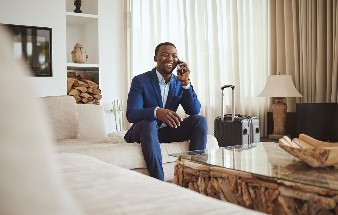happy businessman sitting in a hotel room with suitcase